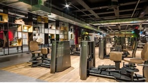 Ett gym med olika typer av träningsutrustning, trägolv och en modern, industriell design.