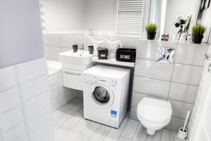A modern bathroom with a washing machine, toilet, and sink. - Residence Aparthotel (Szczecin)