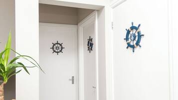 A hallway with a potted plant, a white door, and three wall-mounted ship's wheel decorations.