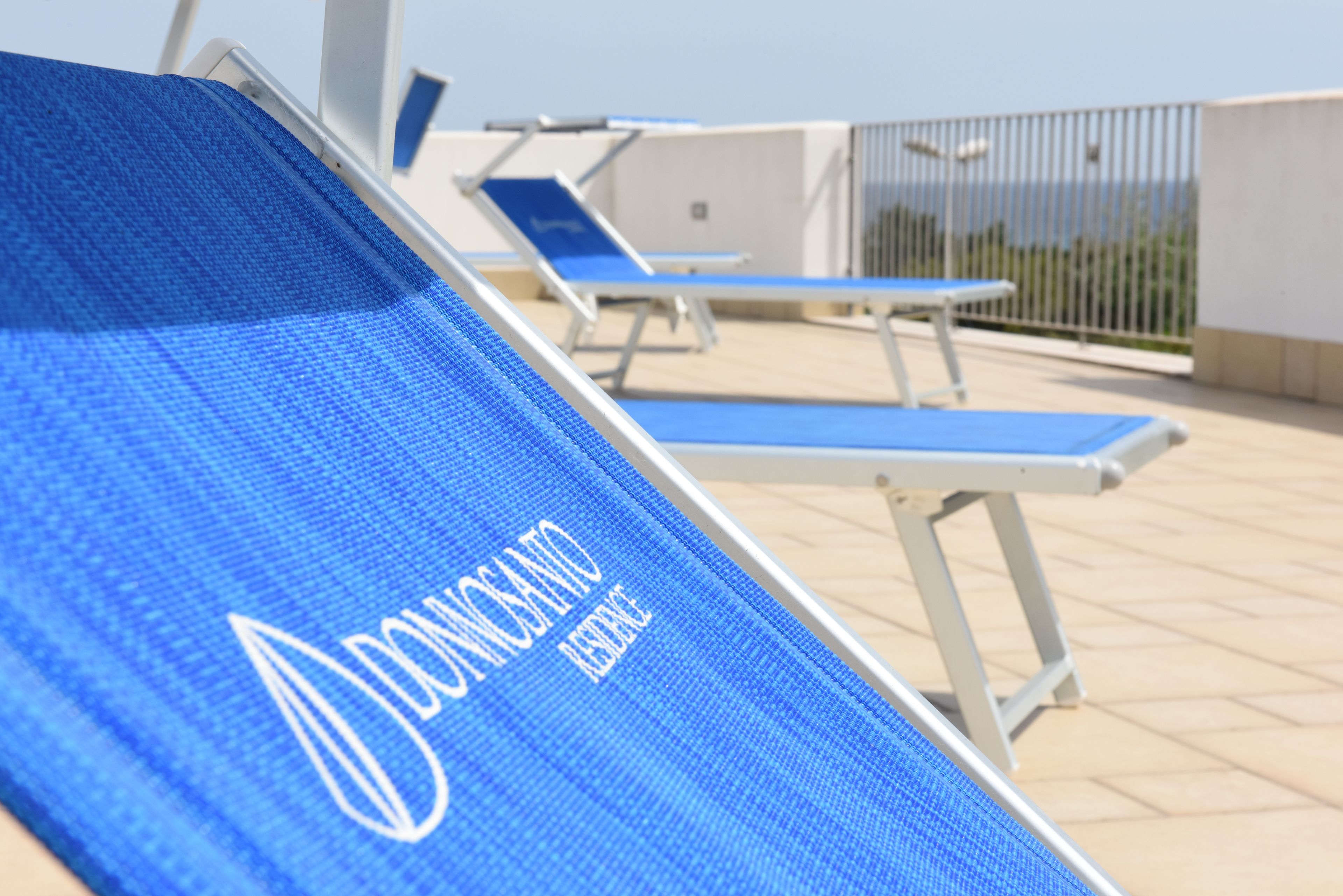 A poolside area with blue lounge chairs and a blue towel with text.