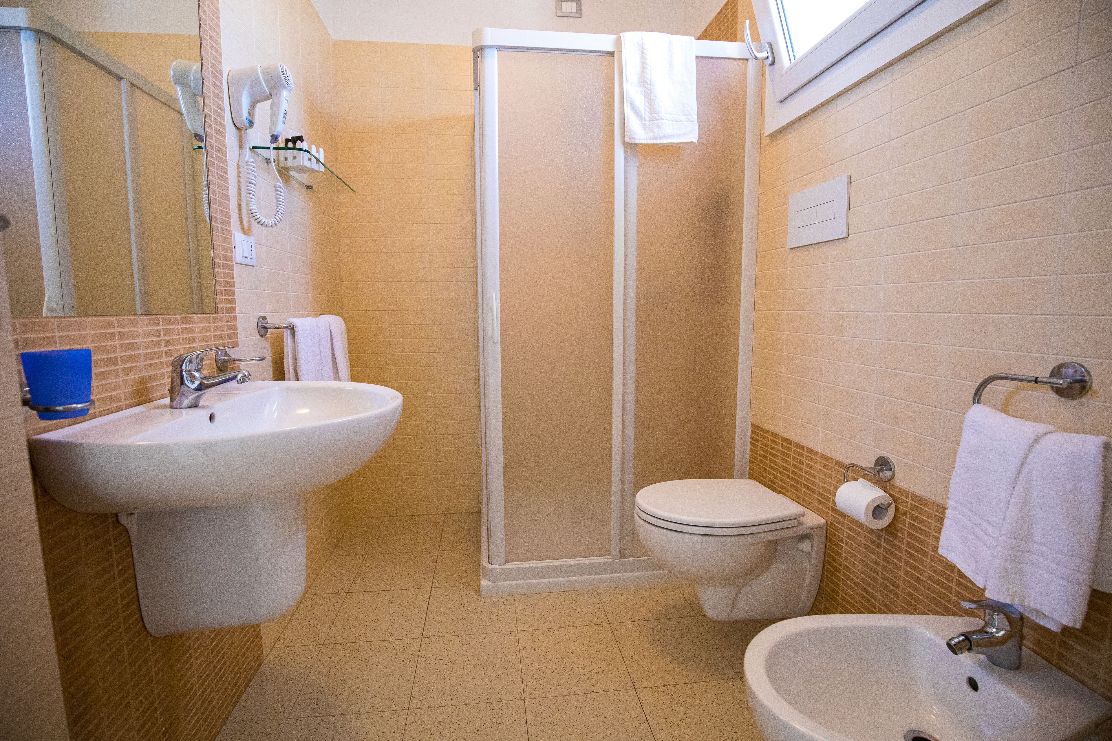 A bathroom with a shower, toilet, sink, and bidet.