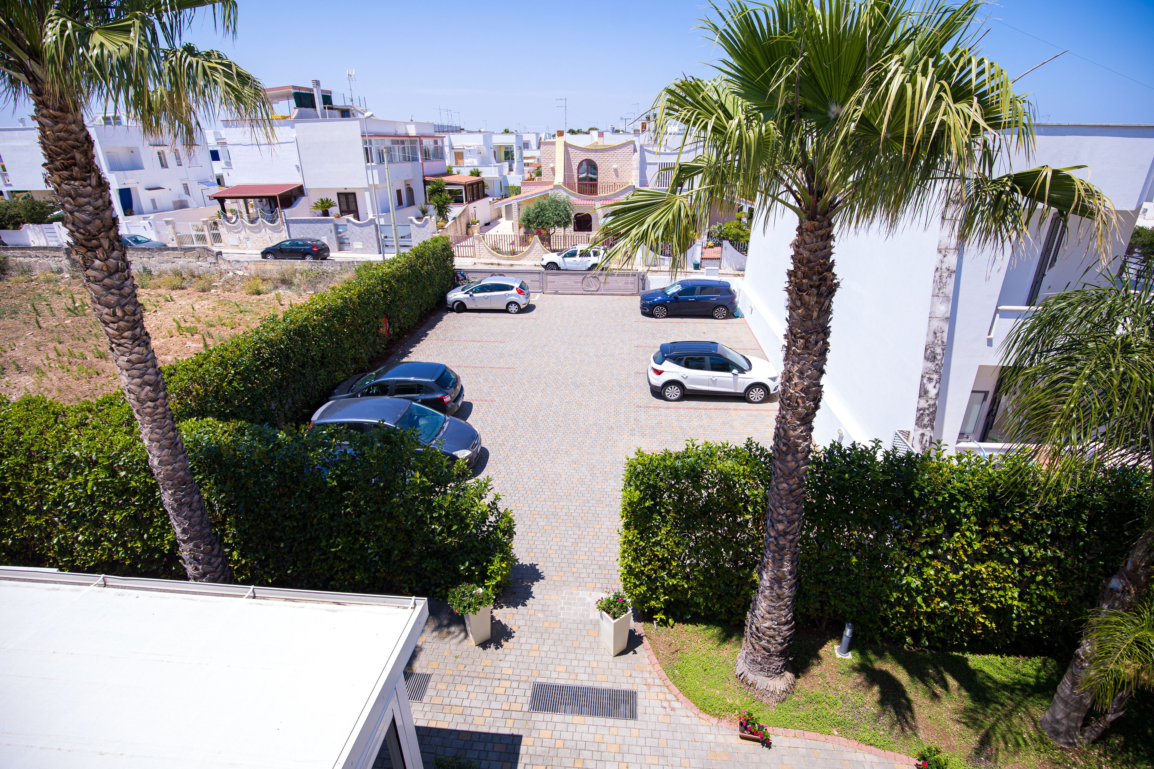 Zona residencial con coches aparcados, palmeras y edificios modernos.