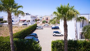 Une rue résidentielle bordée de voitures garées, de palmiers et de maisons blanches.