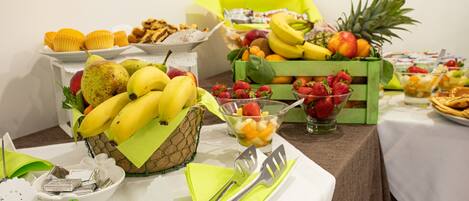 A buffet table with various fruits, pastries, and snacks.