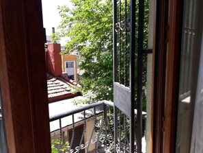 Udsigt fra en balkon med gelænder, der viser et boligområde med huse og træer.