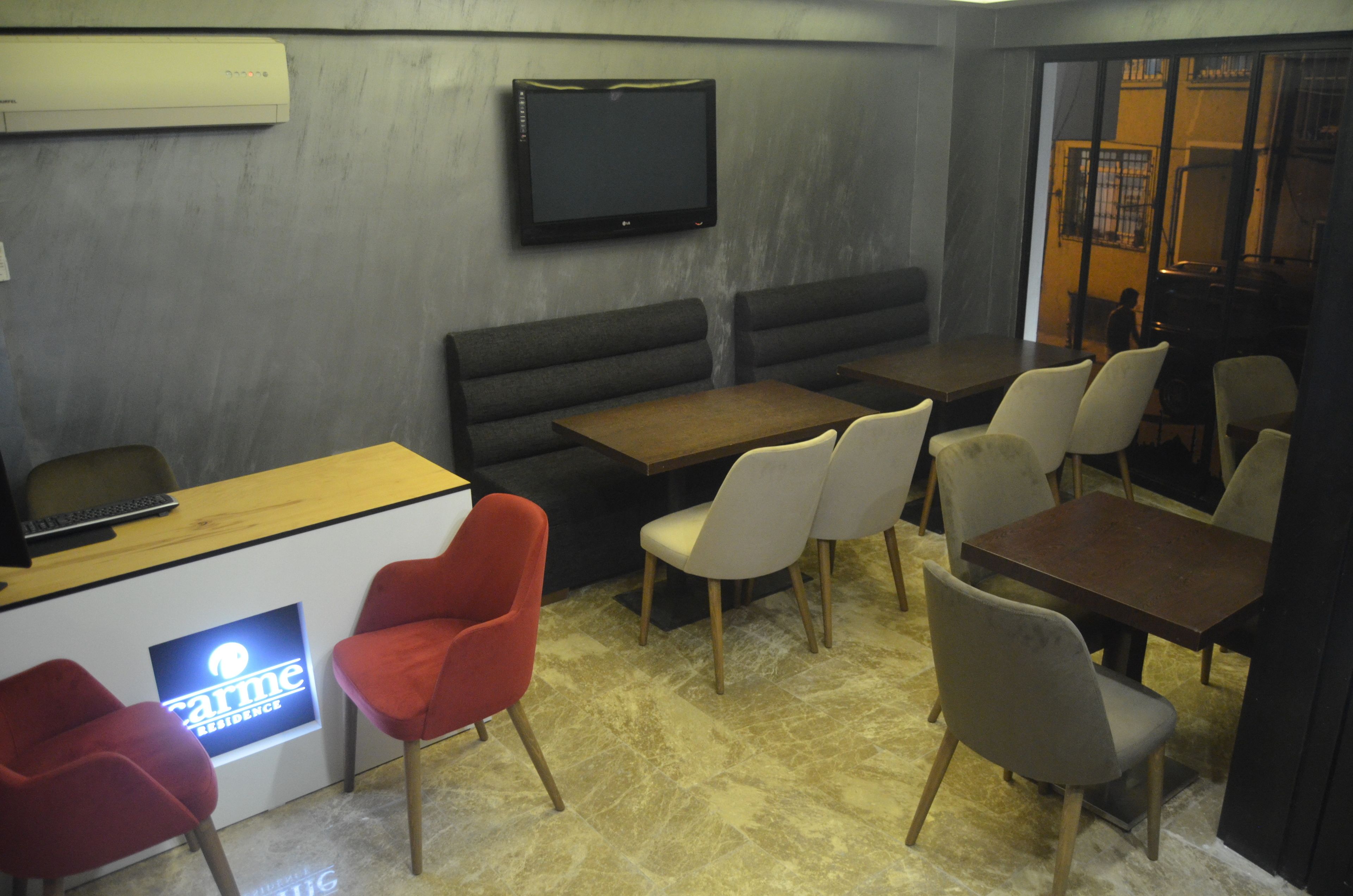 A modern interior with a reception desk, seating area, and a flat-screen TV mounted on the wall.
