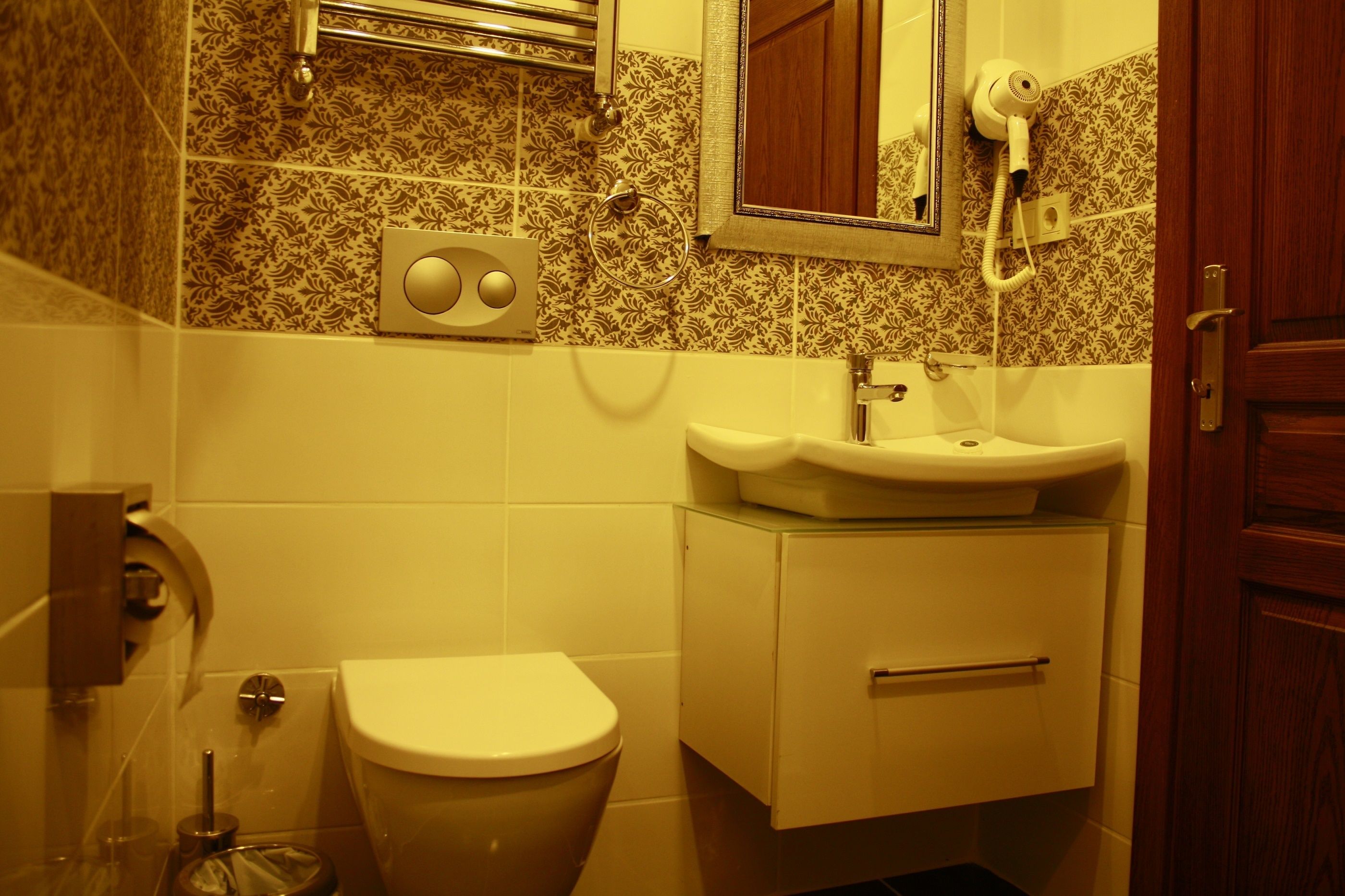 A bathroom with a toilet, sink, and mirror.