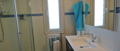 Un baño con cabina de ducha de vidrio, un lavabo con espejo y una ventana con vistas.