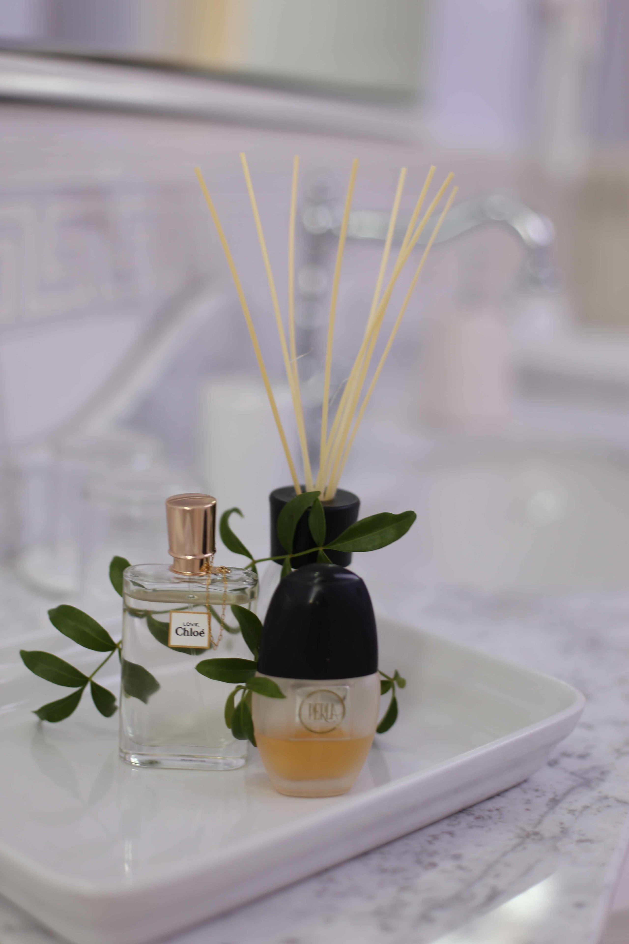 Two perfume bottles on a white tray with reed sticks.