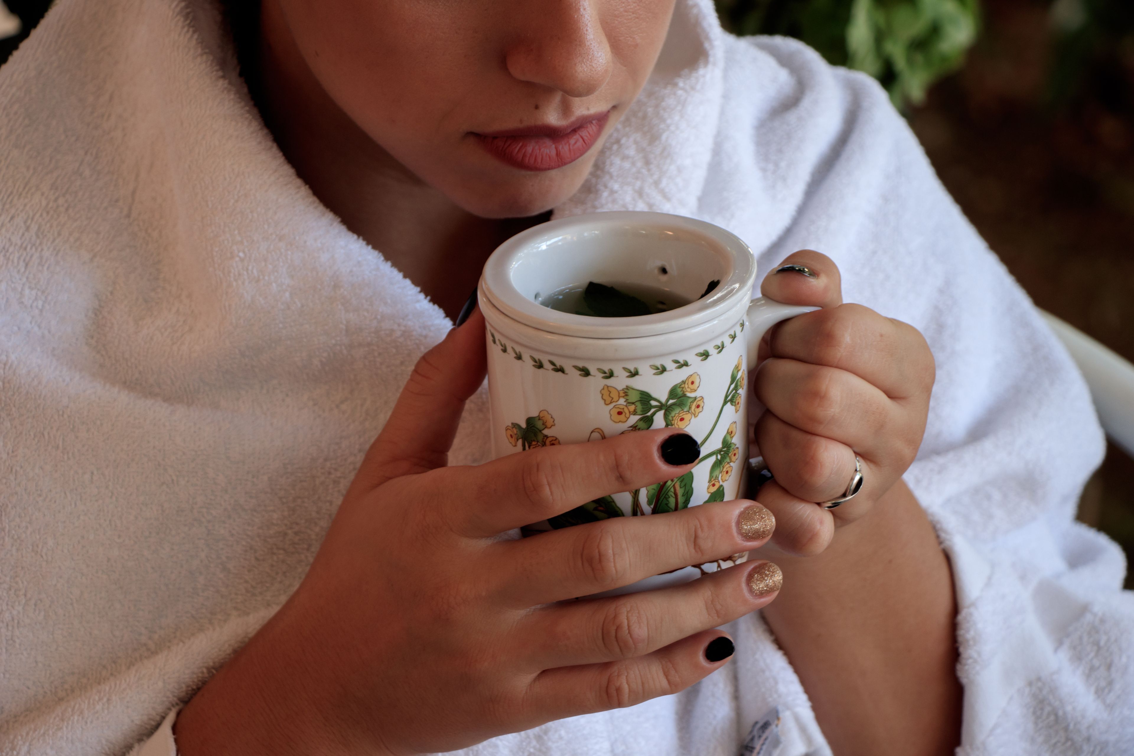 A person holding a ceramic mug with a floral pattern.