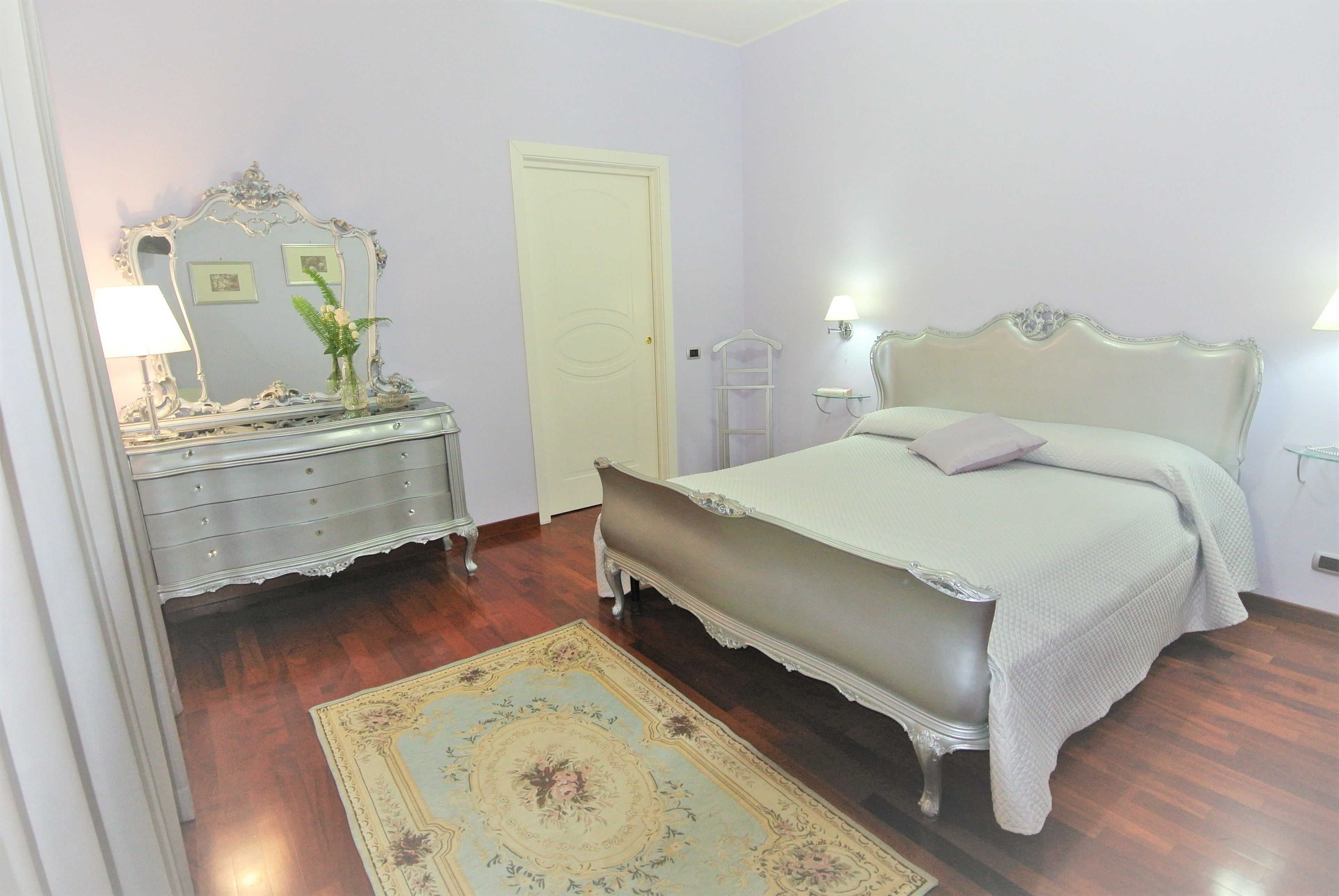 Un dormitorio con cama, cómoda, espejo y una puerta.