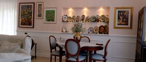 A dining area with a table set for four, surrounded by chairs, and a wall decorated with framed artwork and plates.