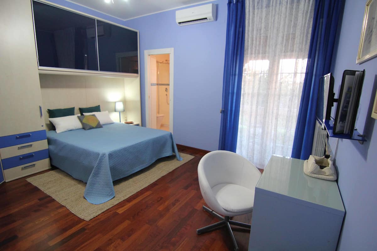 Un dormitorio con cama, mesita de noche, silla y escritorio.