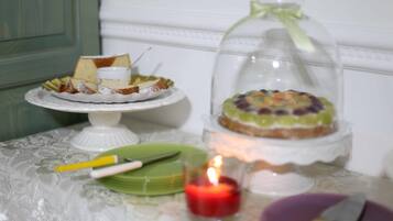 A table with a cake on a stand, a candle, and a knife.