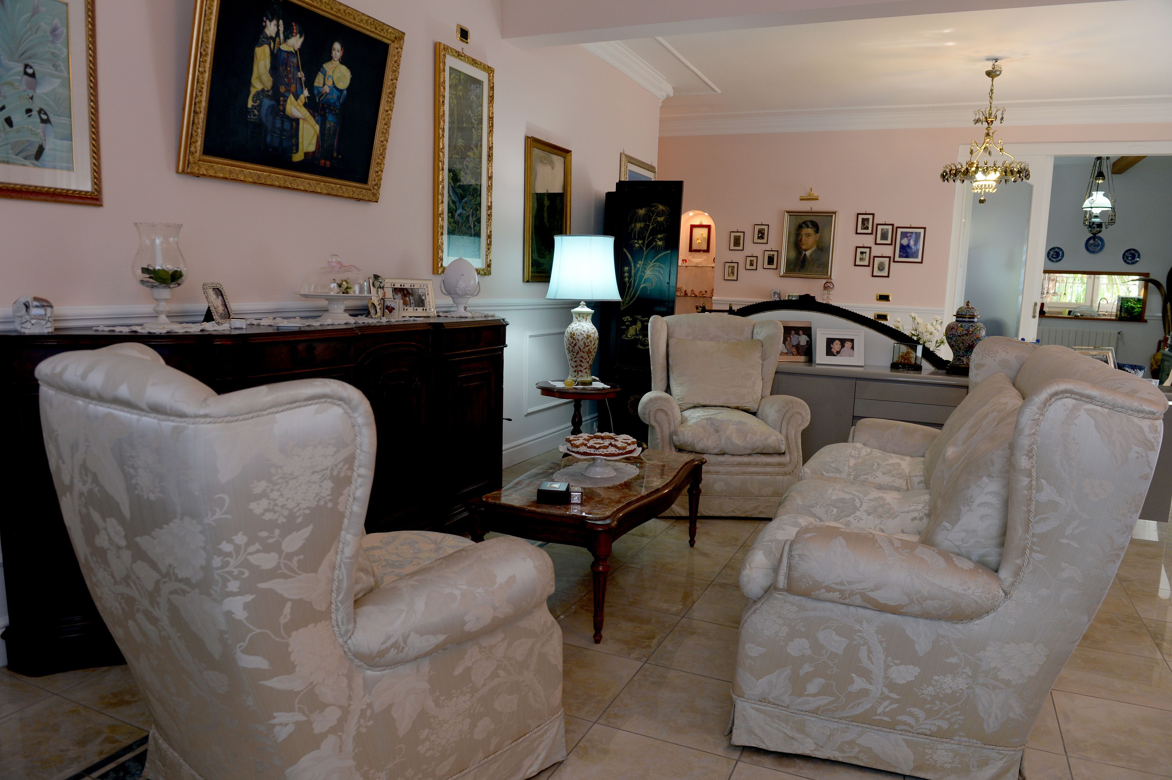 Een woonkamer met een open haard, een eettafel en verschillende fauteuils.