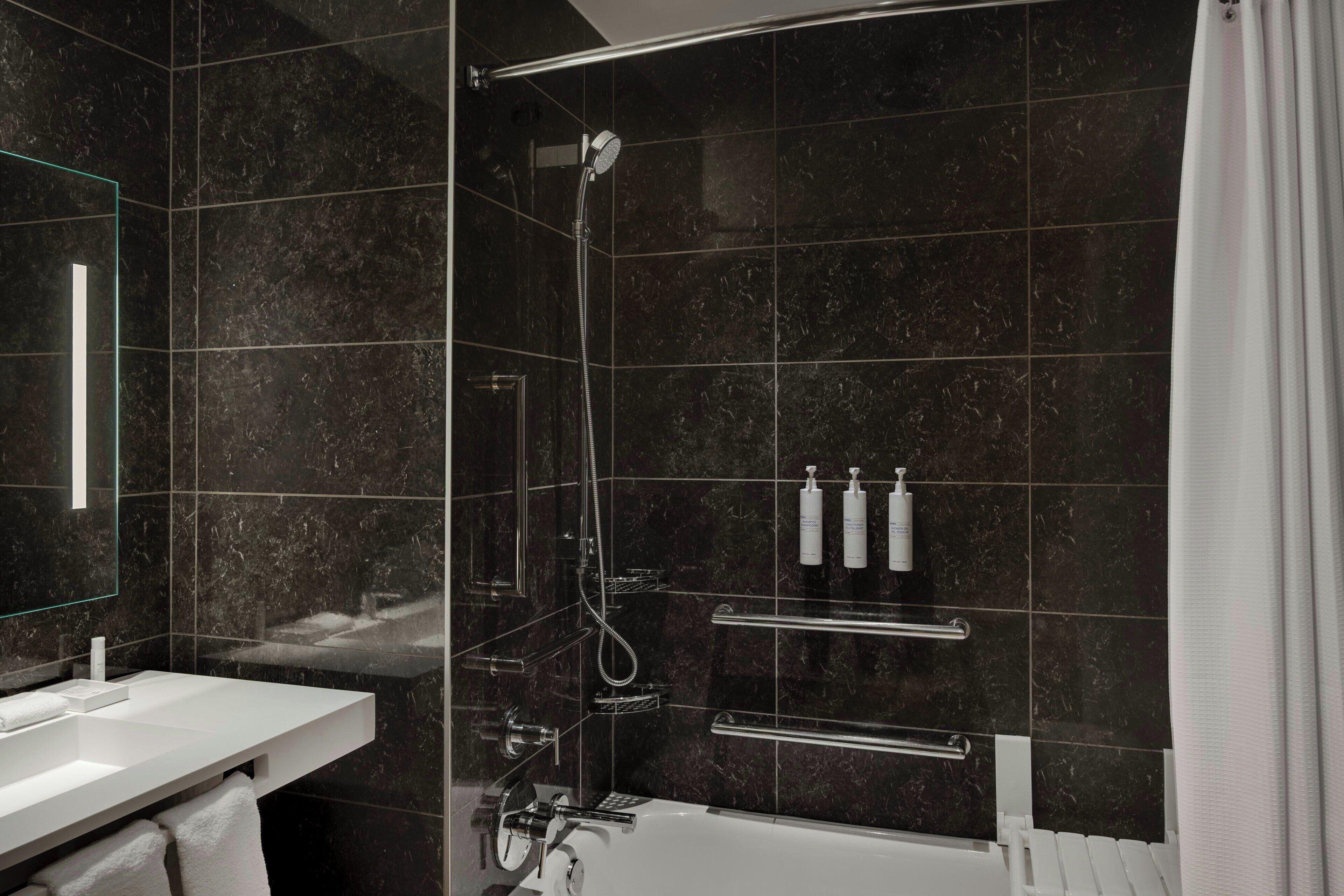 Une salle de bain moderne avec une douche à parois de verre, un lavabo blanc et un miroir.