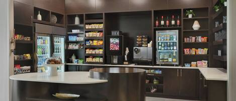 Cozinha moderna com armários de madeira escura, uma ilha central e diversos alimentos e bebidas.