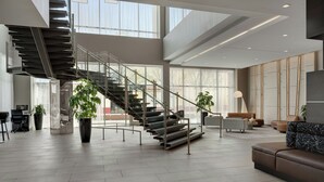 Un interior espacioso con una escalera moderna, ventanas amplias y muebles contemporáneos.