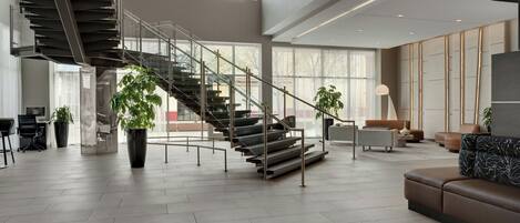 A spacious interior with a modern staircase, large windows, and contemporary furnishings.
