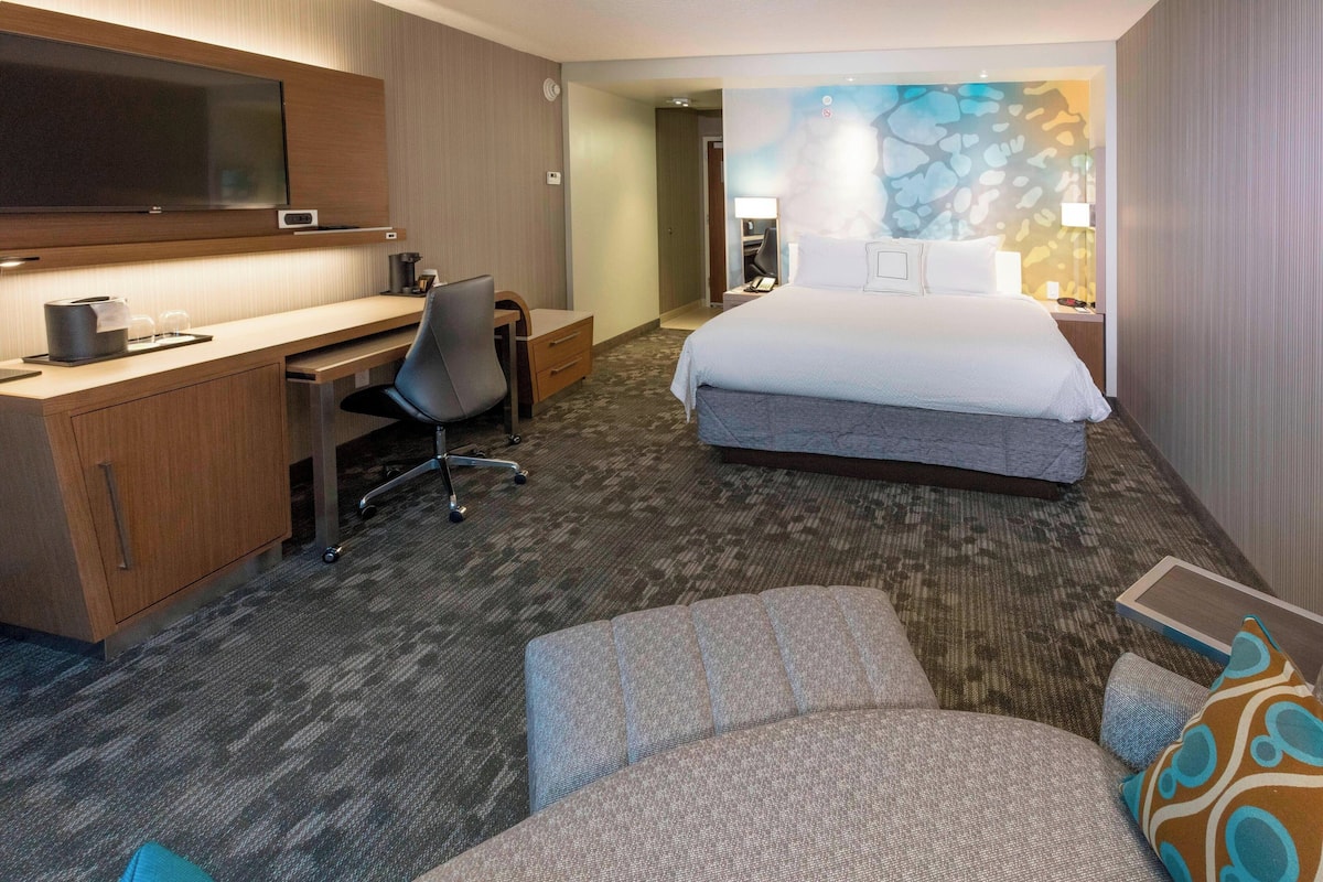 Een hotelkamer met een bed, bureau, stoel en een televisie.