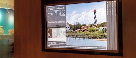 A digital display with a weather forecast, a lighthouse image, and a hotel name.