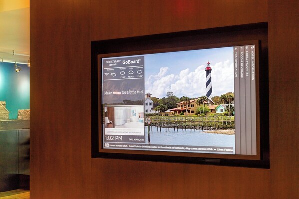 A digital display with a weather forecast, a lighthouse image, and a hotel name.