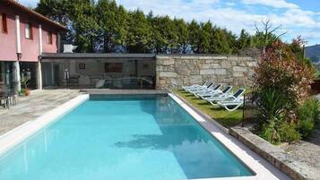Relax by the clear pool surrounded by lush greenery and lounge chairs.
