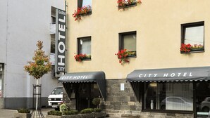 A city hotel with a sign, flower boxes, and a parked van. - City Hotel Fellbach (Fellbach)