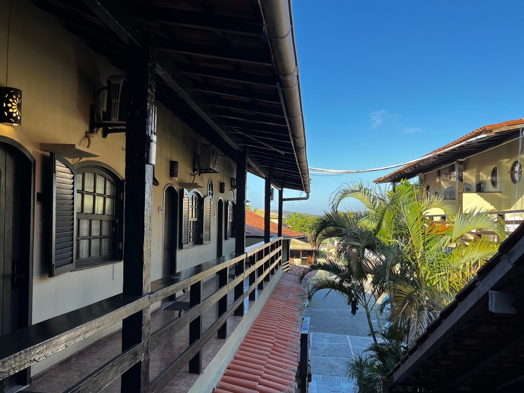 Un edificio con galería techada, ventanas en arco y suelo de baldosas rojas.