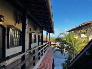 A building with a covered walkway, arched windows, and a red-tiled floor. - Búzios Centro Hotel (Búzios)