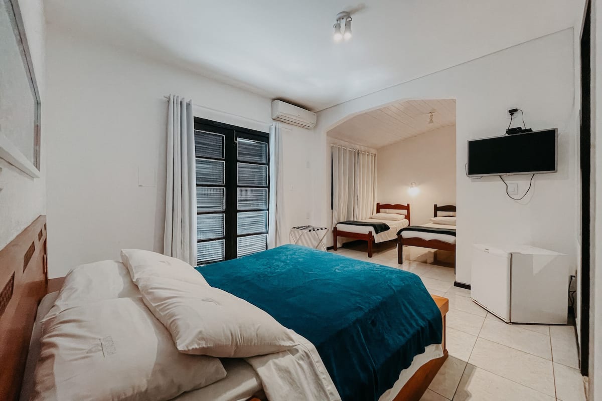 A bedroom with a bed, a TV, and a small kitchenette.