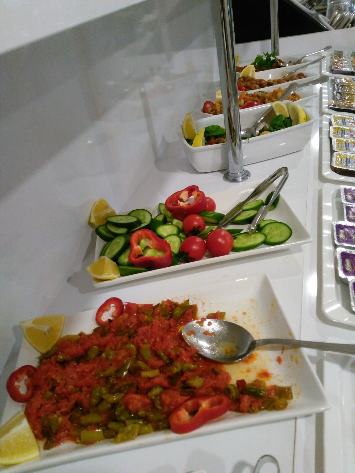 A buffet with various dishes including salads, vegetables, and a tomato-based dish.