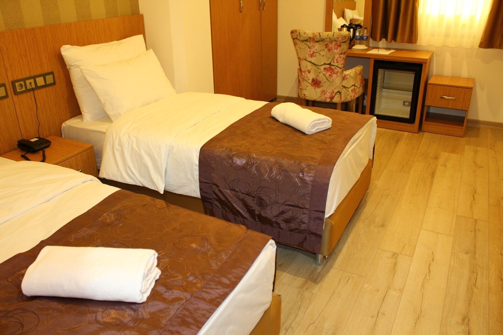Ett hotellrum med två sängar, ett skrivbord med en stol och ett litet bord med en spegel.