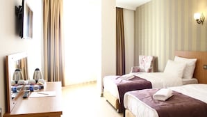 Une chambre d’hôtel avec deux lits, un bureau avec un miroir et une télévision.
