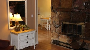 A cozy room with a stone fireplace, a white dresser with a mirror, and a wooden floor. - Kentucky Lake Resort & RV Park (Gilbertsville)