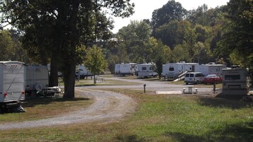 Un camping con vehículos recreativos estacionados en filas, mesas de picnic y un camino de grava.