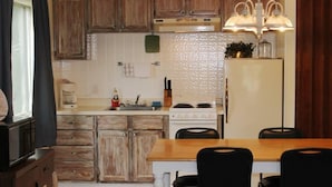 A kitchen with wooden cabinets, a stove, a refrigerator, and a dining table with chairs. - Kentucky Lake Resort & RV Park (Gilbertsville)