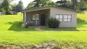 A single-story, light-colored building with a green roof, a front door, and a small porch with two chairs. - Kentucky Lake Resort & RV Park (Gilbertsville)