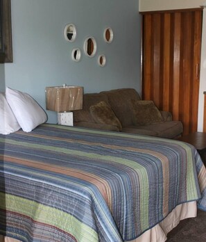 Une chambre à coucher avec un lit, une armoire en bois et une table de chevet avec une lampe.