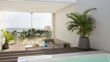 Een balkon met uitzicht op de oceaan, een bank, een potplant en een tafel met een glas wijn.