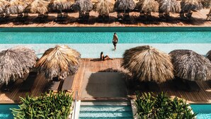 A resort pool area with a wooden deck, thatched umbrellas, and lounge chairs. - Excellence Carmen Punta Cana - Adults Only All Inclusive (Punta Cana)