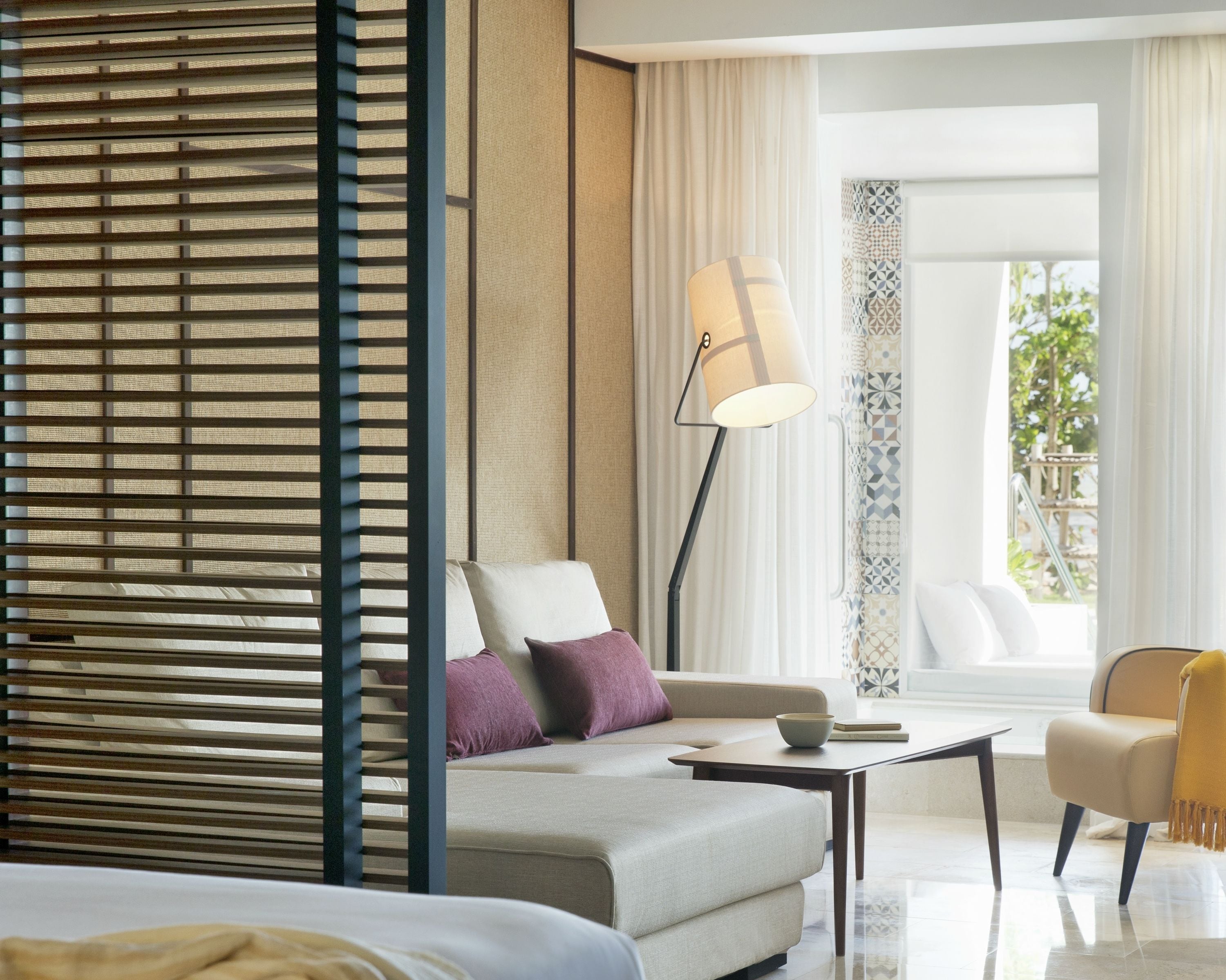 A modern hotel room with a sofa, a coffee table, and a lamp.