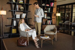 A modern interior with a seating area, bookshelves, and a lamp.