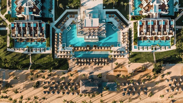 An aerial view of a resort with multiple swimming pools, a beachfront, and a central courtyard. - Excellence Carmen Punta Cana - Adults Only All Inclusive (Punta Cana)
