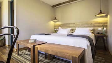 Een netjes ingerichte slaapkamer met een houten hoofdbord, een bed met witte lakens, een nachtkastje met een lamp en een stoel.