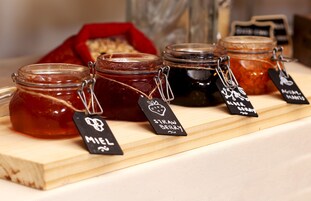 A display of various jars of preserves on a wooden board with labels.