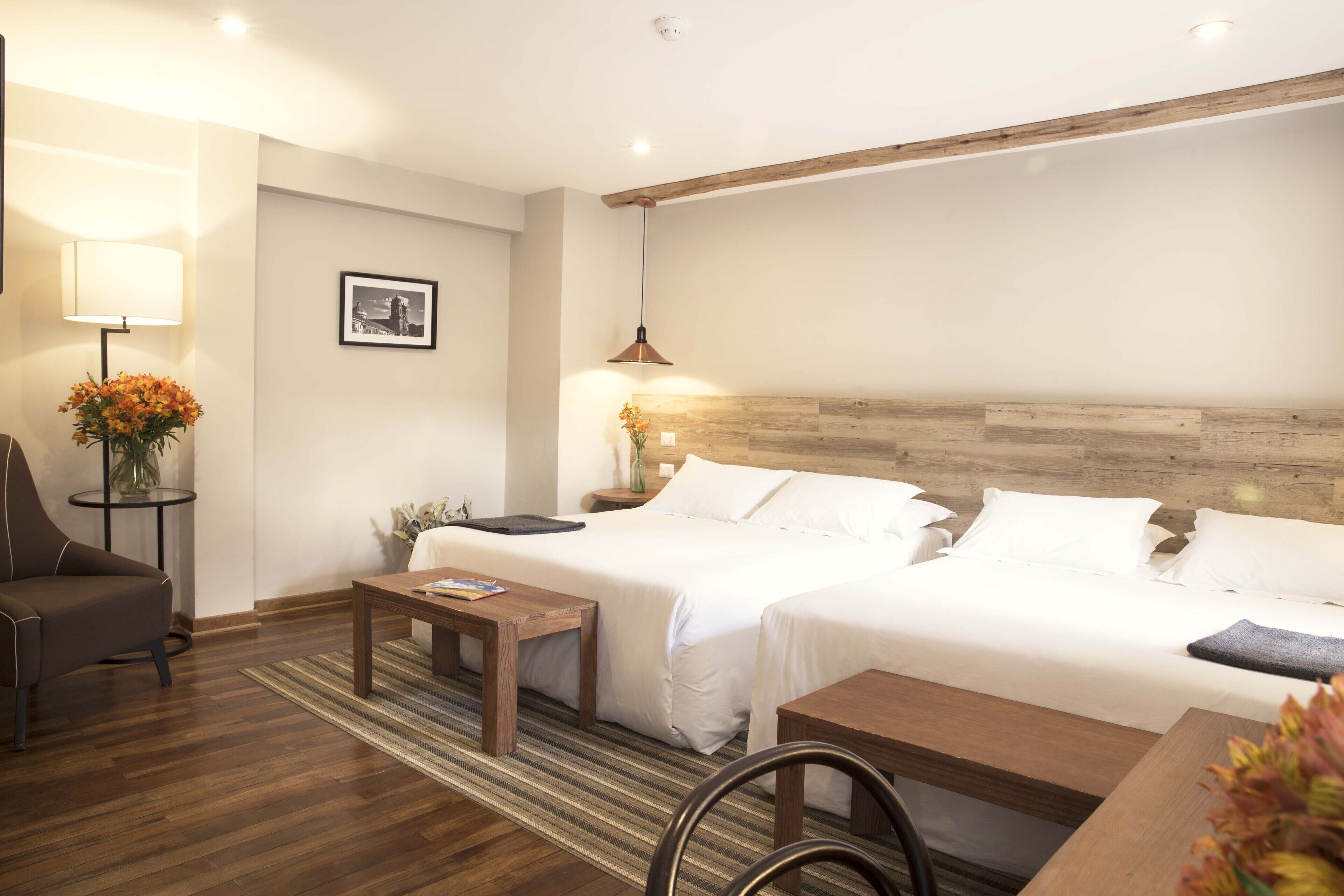 A hotel room with two beds, a sofa, a table, and a lamp.