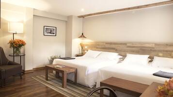 Une chambre d’hôtel avec deux lits, un canapé, une table et une lampe.