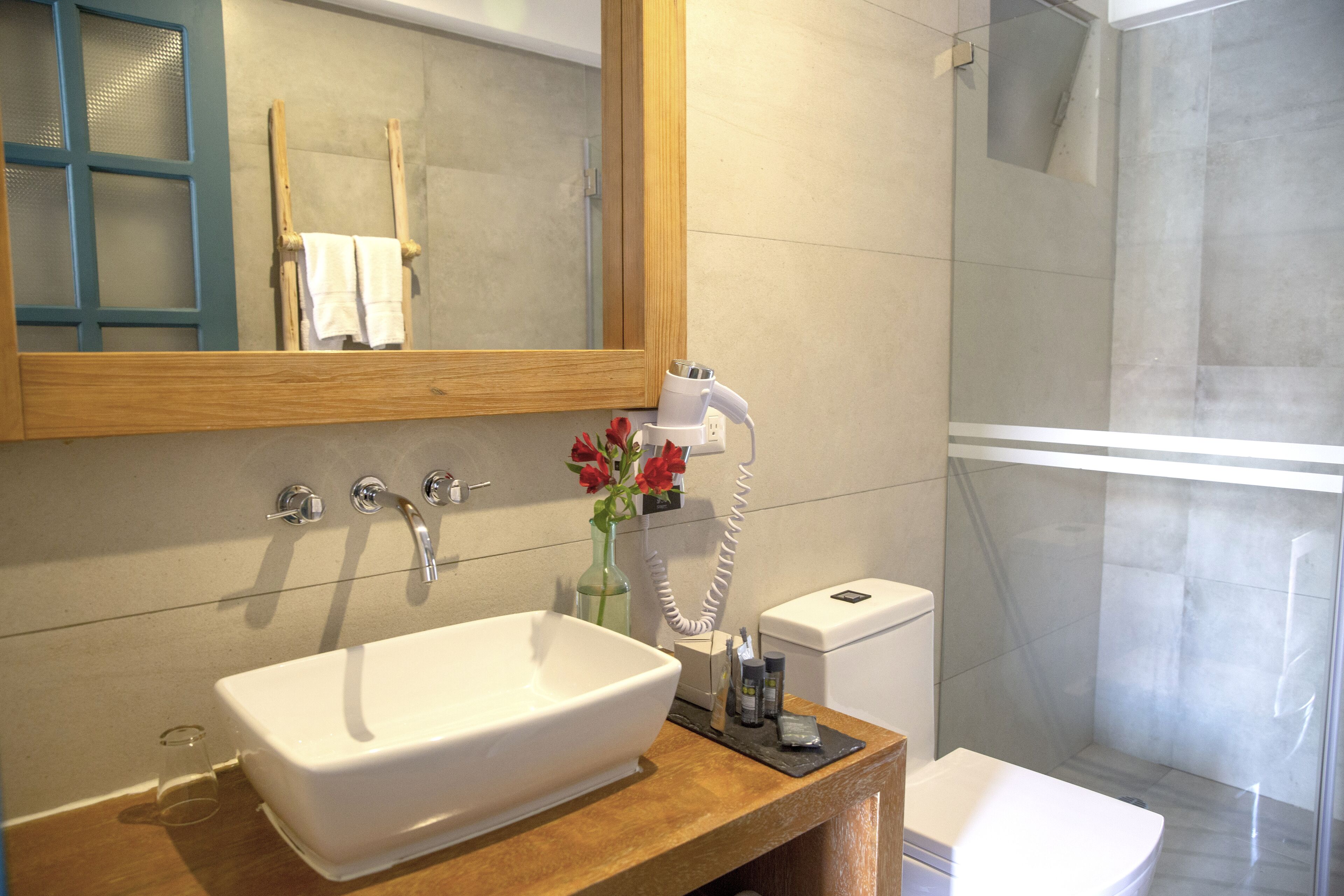 Une salle de bain avec un grand miroir, un lavabo blanc, une douche en verre et des toilettes.