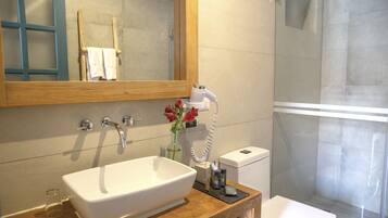 Une salle de bain avec un grand miroir, un lavabo blanc, une douche en verre et des toilettes.